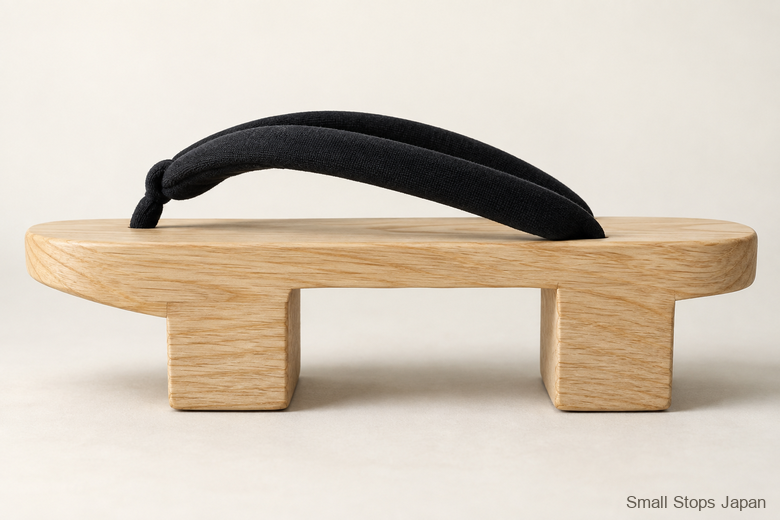 AI-generated side view of one wooden geta with black straps, a horizontal platform and two teeth touching the ground.