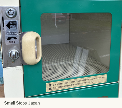 A green produce locker with a window, coin slot and opening controls.