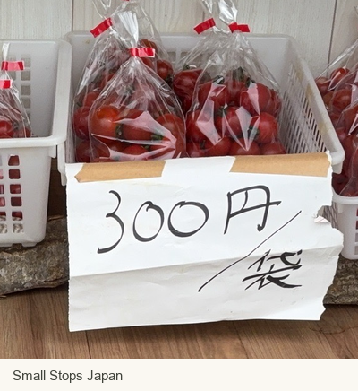 A handwritten label beside bagged tomatoes reads 300 yen per bag.