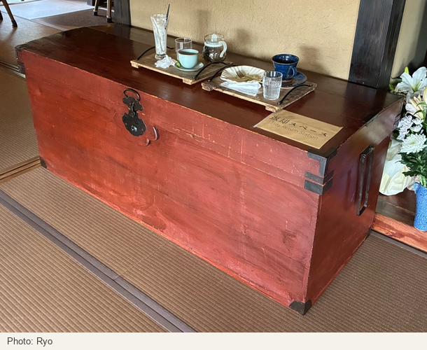 A large wooden chest with metal fittings, trays of used dishes and a return sign.