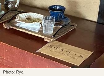 A return sign beside a tray with cups and a used plate on the wooden chest.