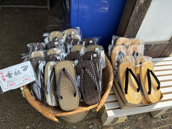 Sandals with patterned straps in a basket beside a sign reading setta.