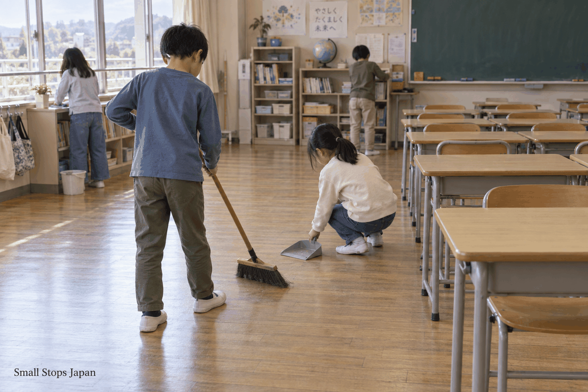Pupils sweep an open classroom floor while individual desks and chairs stand to one side.