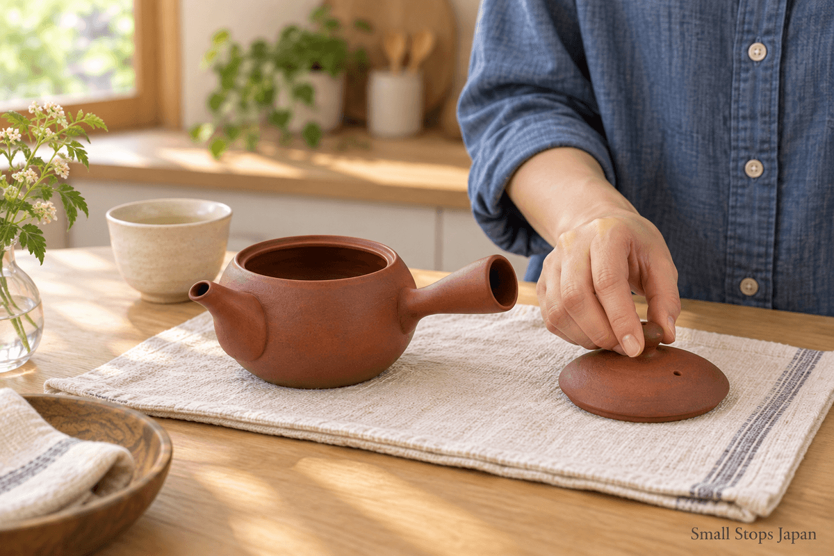 An empty kyusu and its separate lid resting on a clean cloth after washing.