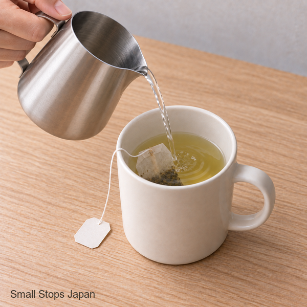 Illustration of a hand holding a steel jug and pouring water into an ivory mug with a tea bag, with the liquid below the rim.
