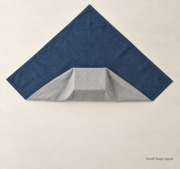 The near corner folded over the box, revealing gray fabric, while the far blue corner and two side corners remain spread out.