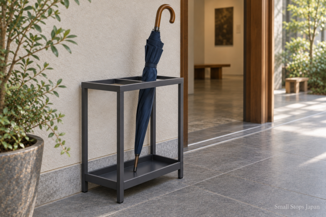 Illustration showing a closed umbrella leaning against an open rack frame with its metal tip resting on the tray.